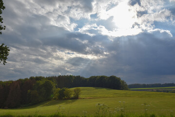 cloudy sky with sunbeams breaking through a field in germany