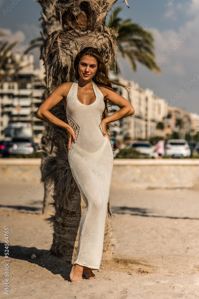 Wall mural Sexy fashion model posing in white dress on the beach.