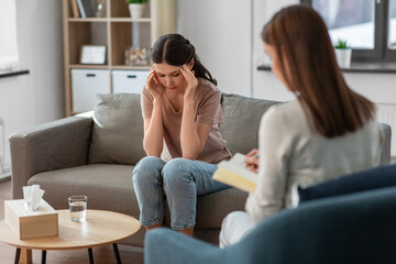 psychology, mental health and people concept - stressed young woman patient and psychologist at...