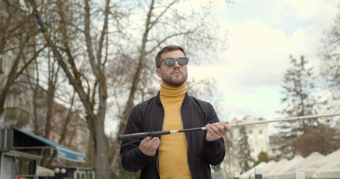 man walking in nature on the side walk holding a stick he is blinded needed directions