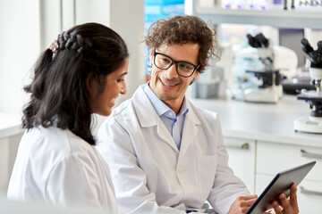 Obraz premium science research, work and people concept - happy international scientists with tablet pc computer working in laboratory