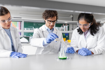 Fototapeta premium science research, work and people concept - international team of scientists with chemicals working in laboratory
