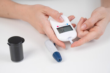 Woman measures blood sugar level with a glucometer. 