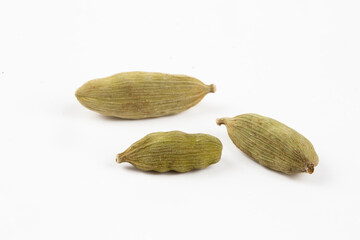 Closeup top view of dried green Elettaria cardamomum fruits with seeds, cardamom spice scattered on white background