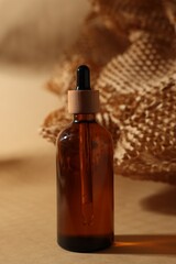 Glass bottle of cosmetic product on dark beige background
