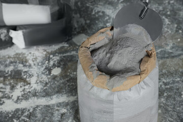 Cement powder and trowel put in bag on stone floor. Space for text