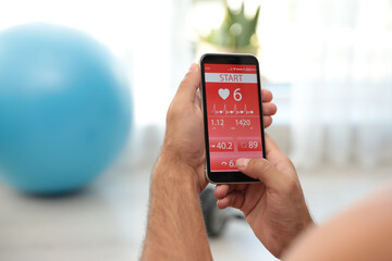 Man using fitness app on smartphone indoors, closeup