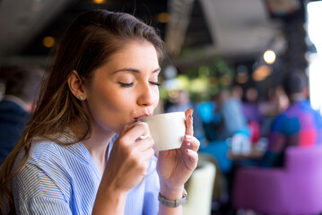 Young woman drinking coffee in the coffee shop