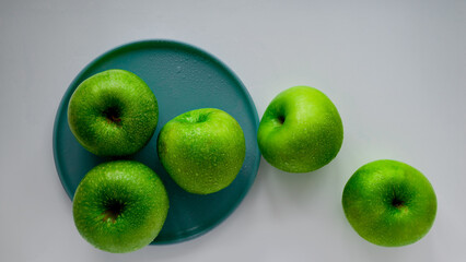 Five green appels and turquoise plate