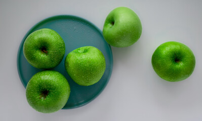 Five green appels and turquoise plate