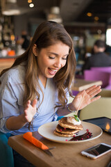 Young woman eating pancakes in the restaurant