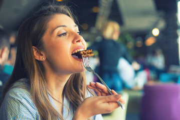 Young woman eating pancakes in the restaurant