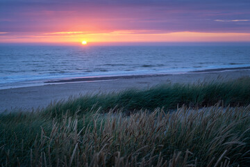 Sonnenuntergang über der Nordsee mit Strand und Düne im Vordergrund