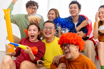 Group of Asian man and woman friends watching soccer games national competition on television with...