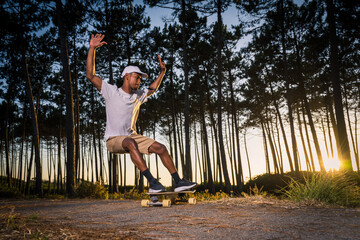 Surf skater performing a slide by the pine forest at sunset