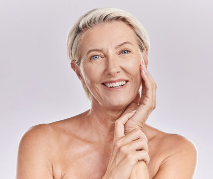Portrait of happy smiling mature caucasian woman looking positive and cheerful against studio background. Smooth face and skin of an older female or antiaging beauty model doing her skincare routine