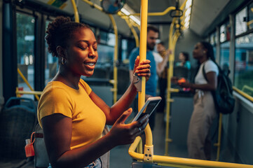 African american woman using smartphone while riding a bus in the night - obrazy, fototapety, plakaty