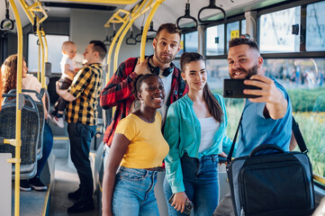 Multiracial group of friends taking selfie with a smartphone in a bus