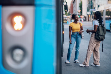 Fototapeta premium Two african american woman waiting for a public transport at a bus stop