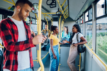 Two young african american female friends standing in a moving bus