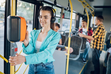 Woman paying a bus ticket via smartphone during a ride