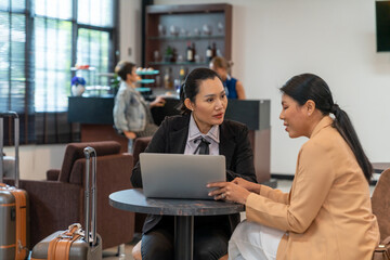 Asian businesswoman working on laptop computer at airport private lounge while waiting for boarding in airport terminal. Airline service business, airplane transportation and holiday vacation concept.