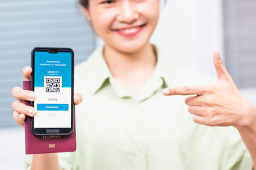 Traveler woman smiling holding health passport of vaccination certification on smartphone