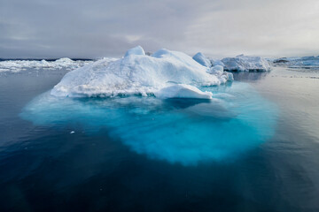 Massive iceberg floating in the Arctic ocean with a clear view of its submerged base.