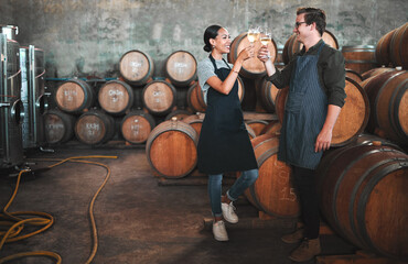 Wine distillery owners cheers glasses in the cellar standing by the barrels. Happy and celebrating...
