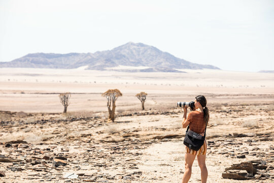 female photographer taking telephoto photos in desert of namibia