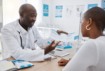 A doctor giving patient hospital information at a clinic and explaining medical benefits to a woman in his office. African American GP or healthcare professional having a discussion with a female - Powered by Adobe