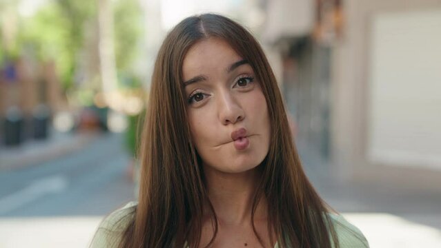 Young beautiful hispanic woman smiling confident doing funny gesture with lips at street
