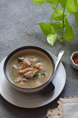a bowl of chicken soup in grey background