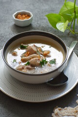 a bowl of chicken soup in grey background