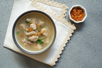a bowl of chicken soup in grey background