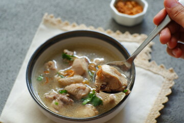 a bowl of chicken soup in grey background