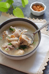 a bowl of chicken soup in grey background