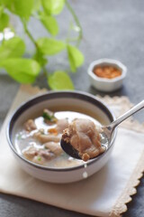 a bowl of chicken soup in grey background