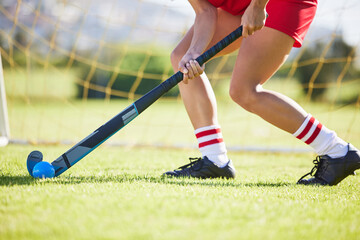 Field hockey, sports and training with a player hitting a ball with a stick and practicing for a match or sport event. Closeup of a sporty athlete being active, healthy and fit while running outside - Powered by Adobe