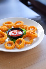 a plate of fried onion rings with tomato sauce 