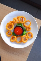 a plate of onion ring with tomato sauce 