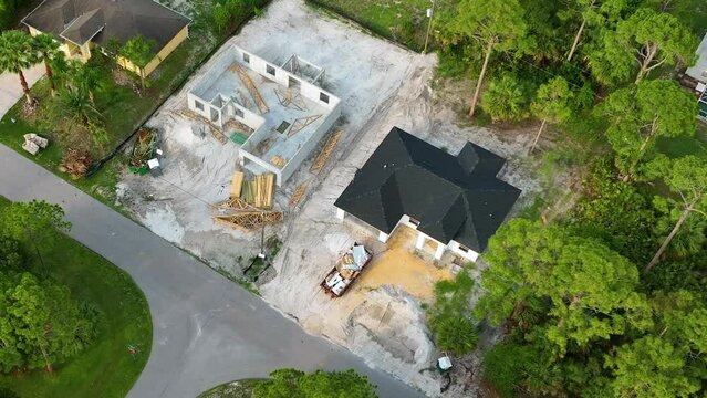 Aerial view of incompleted frame of private home under construction with brick concrete walls ready for installation of wooden roofing beams. Industrial building site