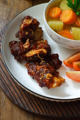 a plate of grilled beef ribs served with vegetables 