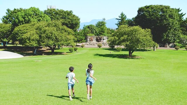 自然豊かな公園を走るアジア人の子供