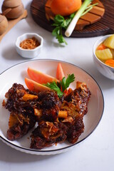a plate of grilled beef ribs served with vegetables 