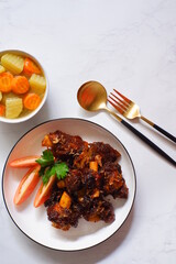 a plate of grilled beef ribs served with vegetables 