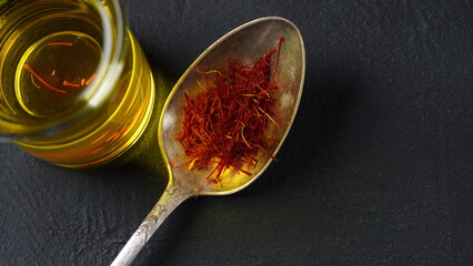 Expensive Red Dried saffron spice in a spoon on dark background
