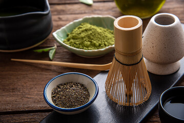 Matcha fine powdered green tea set . Japanese organic matcha green tea powder in bowl with wire whisk on wooden table background.