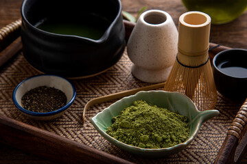 Matcha fine powdered green tea set . Japanese organic matcha green tea powder in bowl with wire whisk on wooden table background.