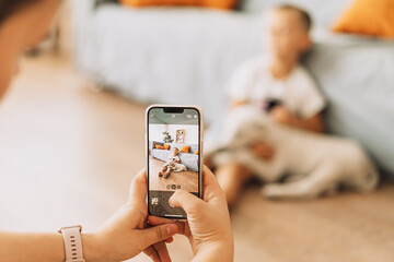The girl takes a picture on the phone of a child with a puppy.